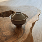 Beige ceramic gaiwan and two cups close-up view on natural wood slab