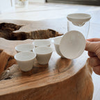 white gaiwan with cha hai pitcher and cups arranged on natural wood surface