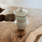 gaiwan tea brewing set with cha hai, strainer, and cups stacked on wooden tray