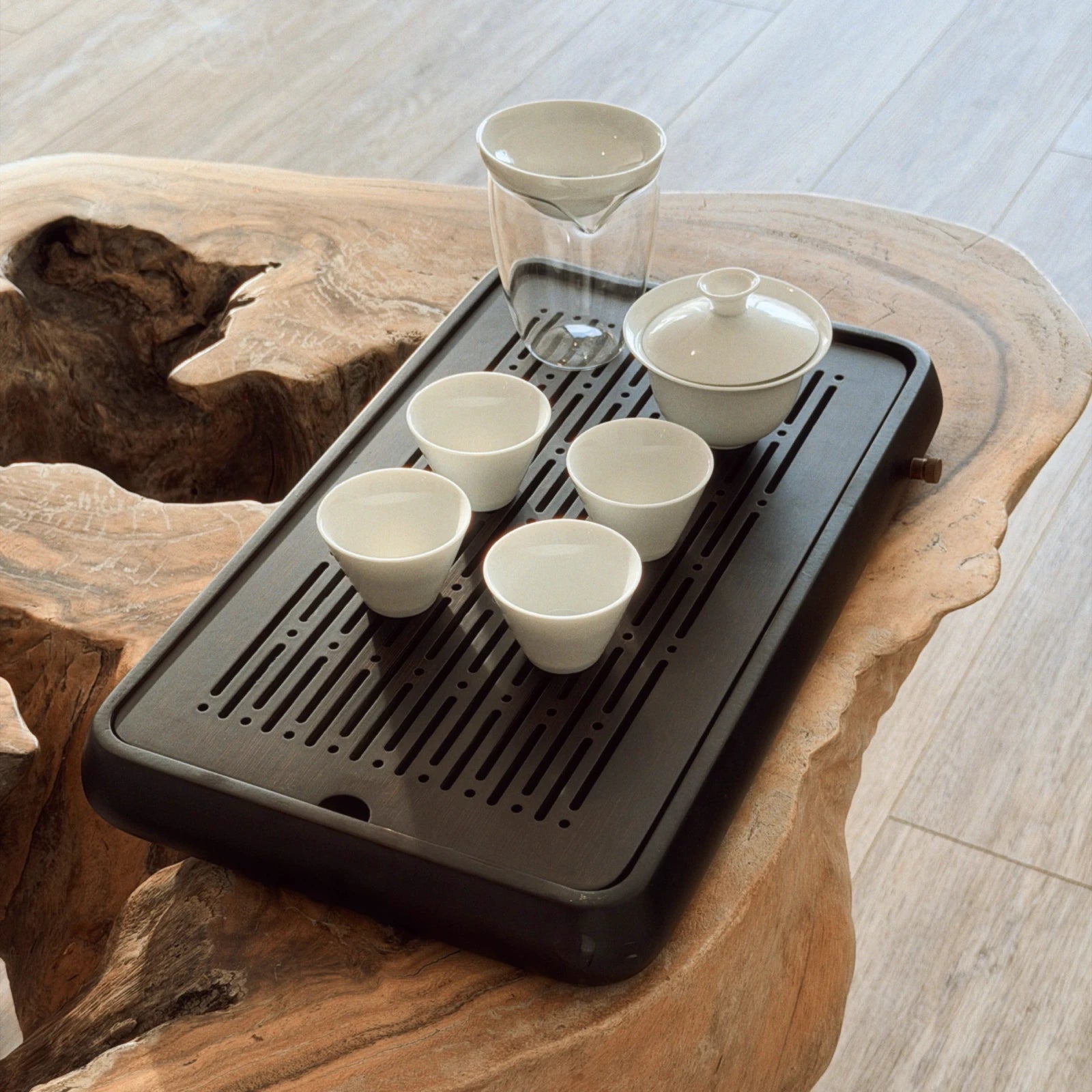 Black chaban tea tray with white gaiwan cups set on wooden surface