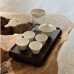 Black chaban tea tray with white gaiwan cups set on wooden surface